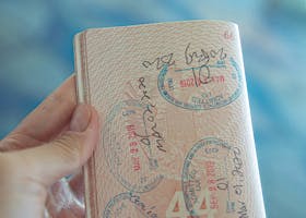 A close-up view of a hand holding an open passport with various stamps, highlighting travel experiences.